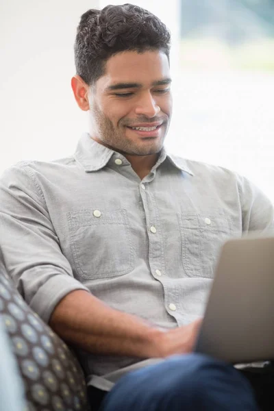 Man sitter på soffan och använder laptop i vardagsrum — Stockfoto