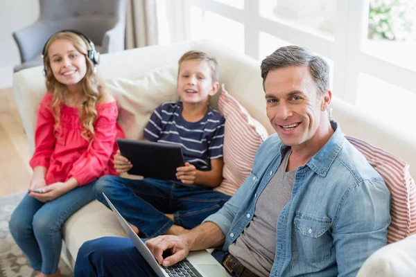 Portrait de père et d'enfants utilisant un ordinateur portable et une tablette numérique dans le salon — Photo