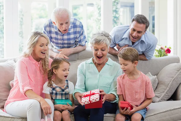Famiglia che apre il regalo a sorpresa in soggiorno — Foto Stock
