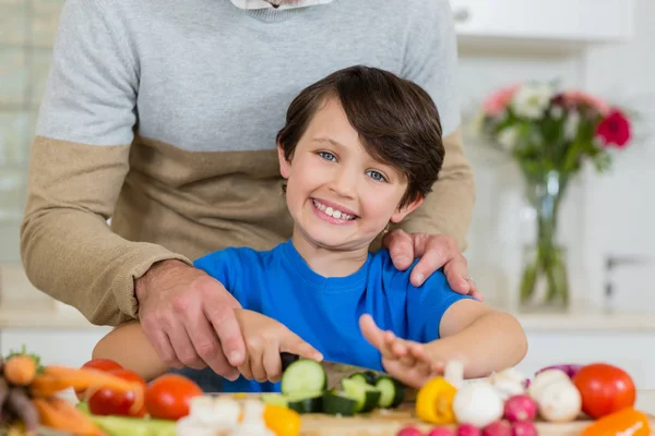 Батько і син нарізають огірок на дошці на кухні — стокове фото