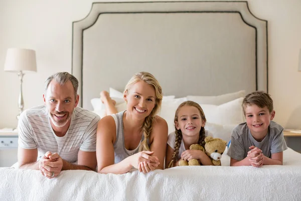 Padres con sus hijos acostados en la cama en el dormitorio —  Fotos de Stock