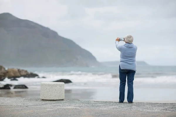 Vezető nő fényképezés táj használ sejt telefon, a strandon — Stock Fotó