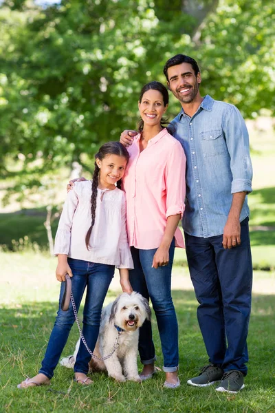 Retrato de familia feliz con su perro mascota de pie en el parque —  Fotos de Stock