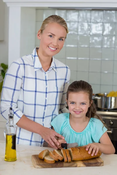 Mamma hjälpa en dotter att skära limpa bröd — Stockfoto