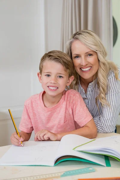 Madre asistiendo hijo haciendo la tarea —  Fotos de Stock