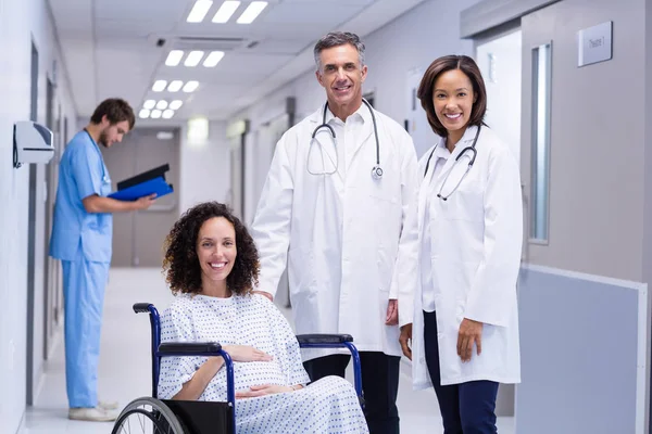 Portrait of doctors and pregnant woman in corridor — Stock Photo, Image