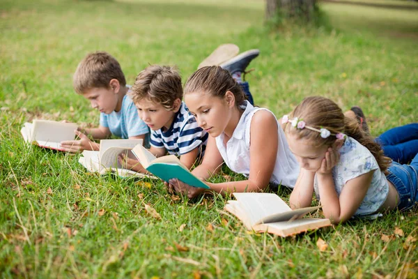 Enfants allongés sur l'herbe et lisant des livres — Photo