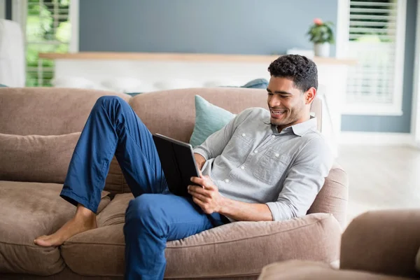 Man sitter på soffan och använda digitala surfplatta i vardagsrum — Stockfoto