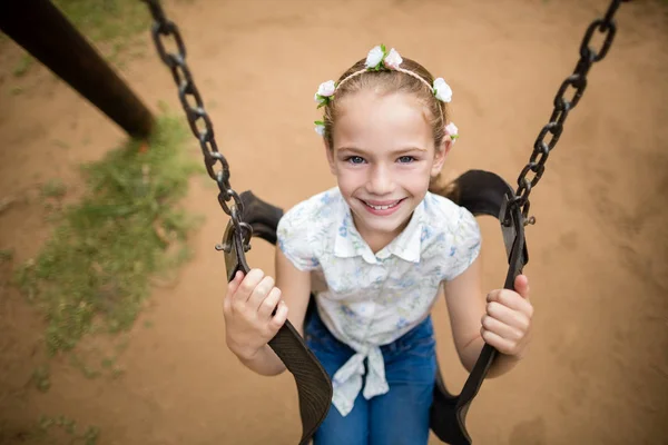 Chica feliz sentada en un columpio en el parque — Foto de Stock