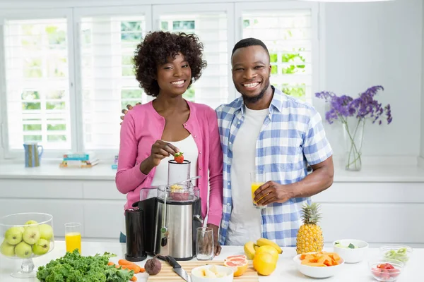 Casal sorridente preparando smoothie de morango na cozinha em casa — Fotografia de Stock