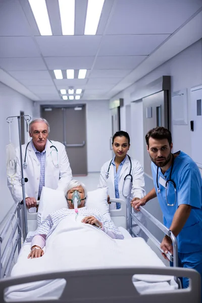 Médico e enfermeira empurrando cama maca de emergência no corredor — Fotografia de Stock