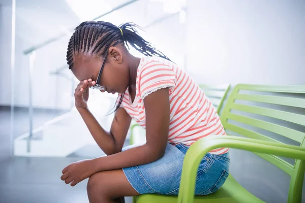 Aufgebrachtes Mädchen sitzt auf Stuhl im Flur — Stockfoto