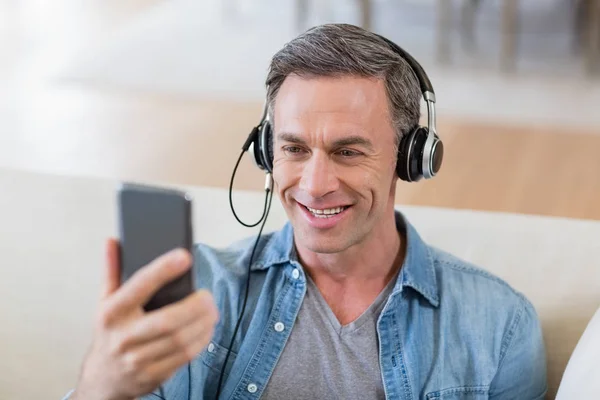 Homme écoutant de la musique sur écouteurs dans le salon à la maison — Photo