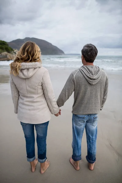 情侣站在一起手牵着手在海滩上 — 图库照片