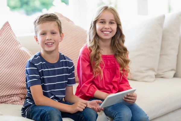 Geschwister nutzen digitales Tablet auf Sofa im Wohnzimmer — Stockfoto