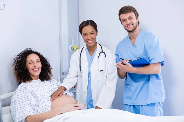 Portrait of doctors examining pregnant woman in ward — Stock Photo, Image