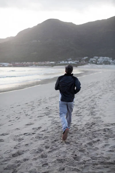 Maturo uomo jogging su il spiaggia — Foto Stock