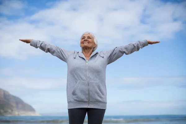 Mujer mayor haciendo ejercicio de estiramiento en la playa —  Fotos de Stock