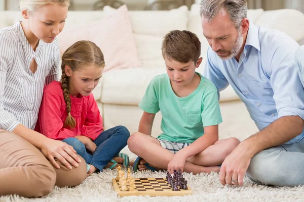 Familj spelar schack tillsammans hemma i vardagsrummet — Stockfoto