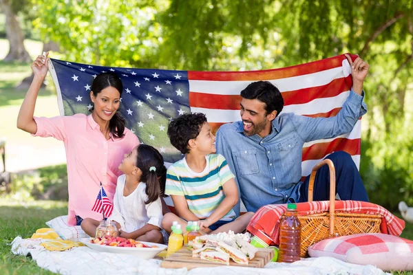 Familia feliz con una bandera americana en el parque — Foto de Stock