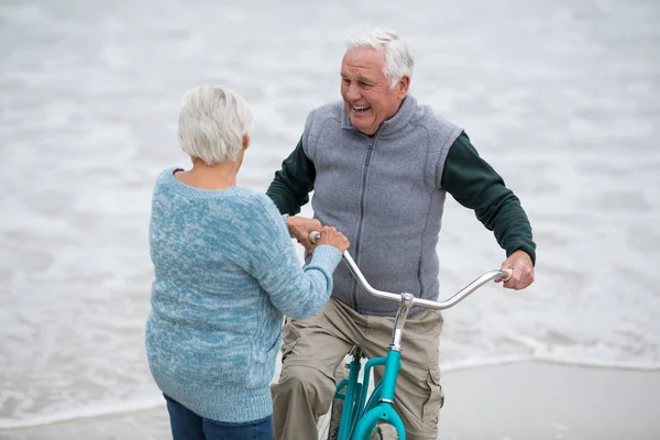 Seniorenpaar steht mit Fahrrädern am Strand — Stockfoto