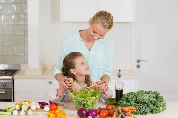 Mother and daughter preparing salad in kitchen — Stock Photo, Image
