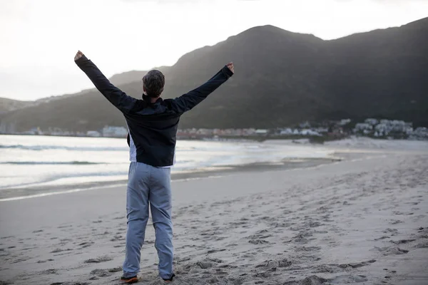 Hombre maduro de pie con los brazos extendidos en la playa — Foto de Stock