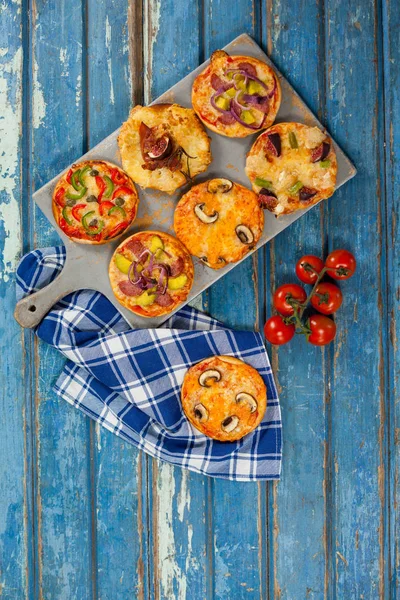 Várias deliciosas pizzas italianas servidas na bandeja de pizza na prancha de madeira — Fotografia de Stock