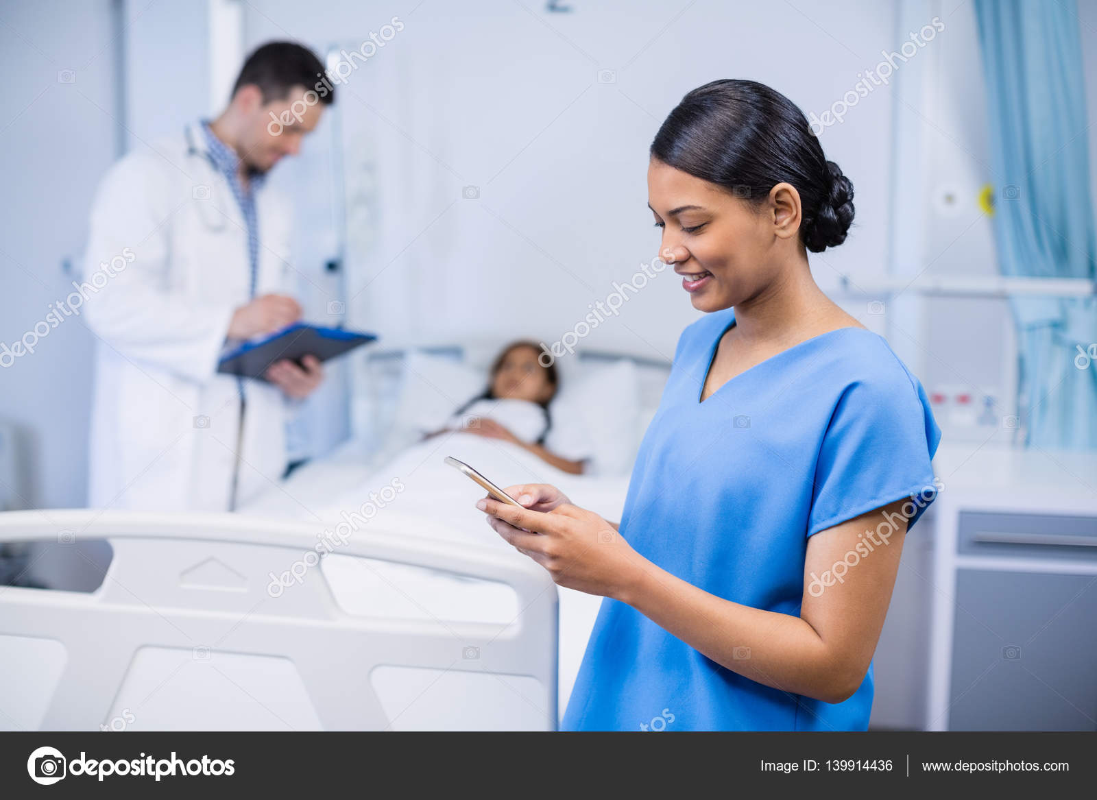 Smiling nurse using mobile phone Stock Photo by ©Wavebreakmedia 139914436