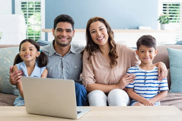 Retrato de padres felices y niños sentados con el brazo alrededor en la sala de estar —  Fotos de Stock