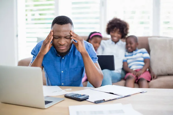 Bezorgd mens zittend aan tafel met facturen en laptop — Stockfoto