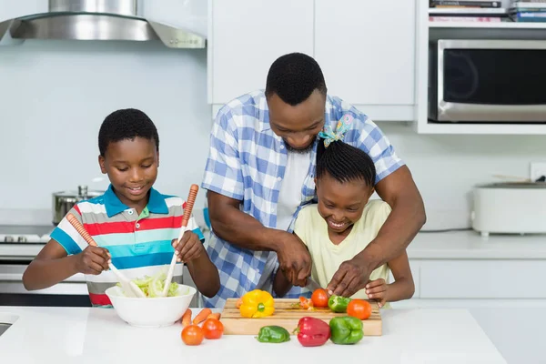 Vader hun jonge geitjes te helpen bij de voorbereiding van de salade in keuken — Stockfoto