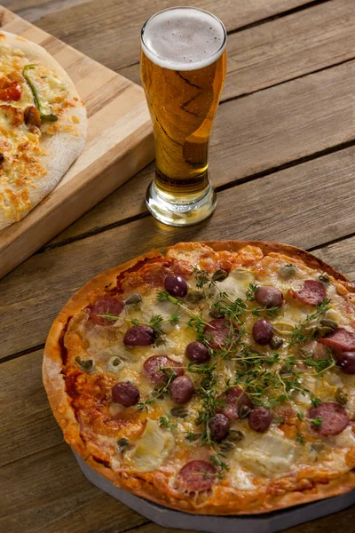 Deliciosa pizza servida sobre tabla de madera con un vaso de cerveza — Foto de Stock