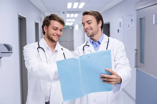 Doctors having discussion on file in corridor — Stock Photo, Image