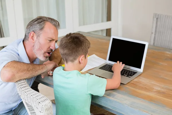Padre ayudar a su hijo mientras usa el ordenador portátil en el escritorio — Foto de Stock