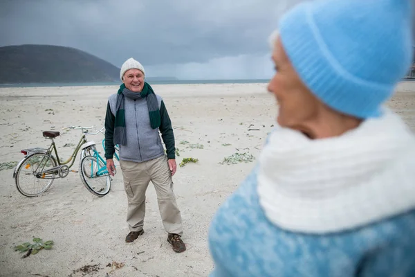 Старша пара стоїть з велосипедами на пляжі — стокове фото