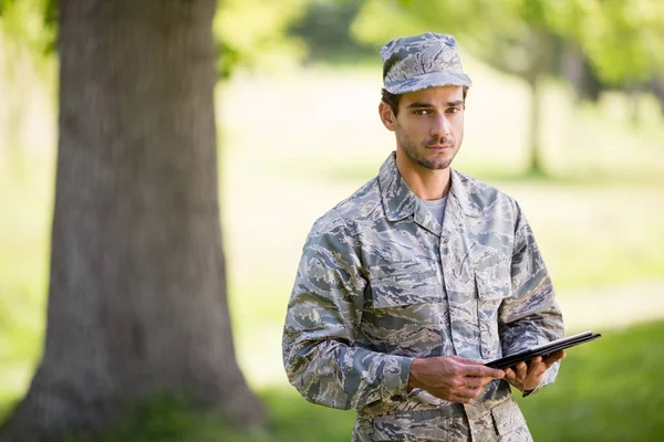 Soldat som holder digitale nettbrett i park – stockfoto