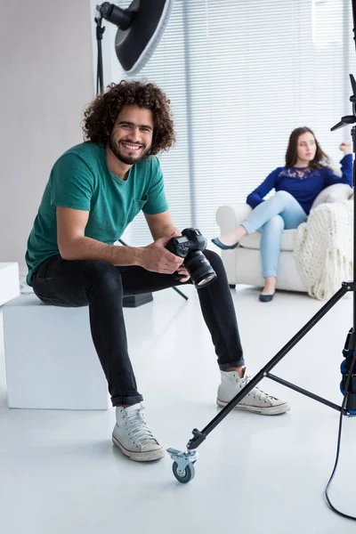 Fotógrafo sentado en el estudio con la cámara — Foto de Stock