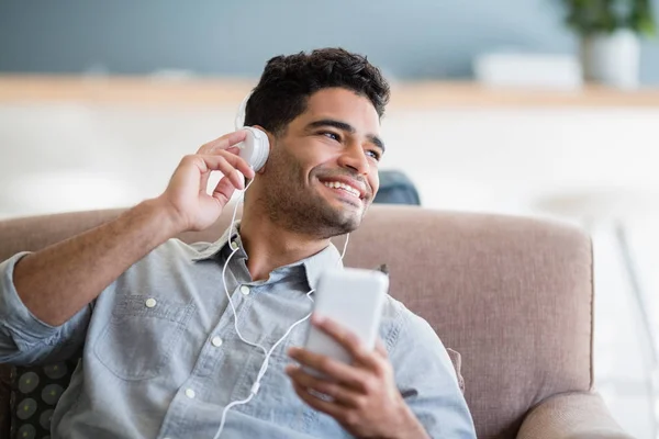 Homem ouvindo música no celular na sala de estar — Fotografia de Stock