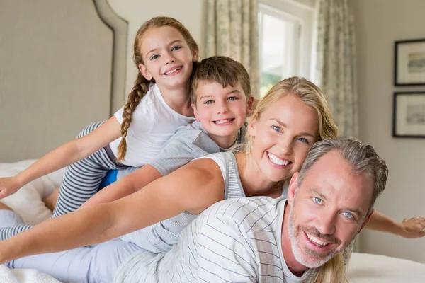 Happy family stacking on top of each other on the bed — Stock Photo, Image