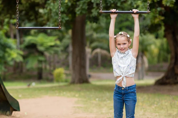 Chica colgando de un equipo de juego en el parque — Foto de Stock