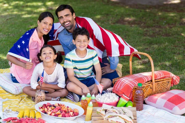 Boldog családi gazdaság egy amerikai zászló park portréja — Stock Fotó
