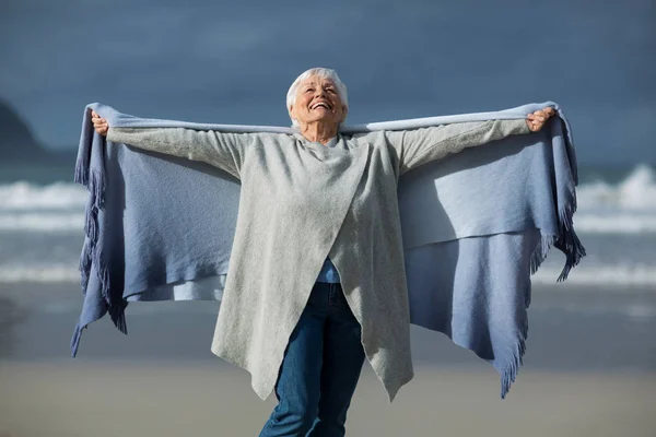 Ler senior kvinna insvept i sjal på stranden — Stockfoto