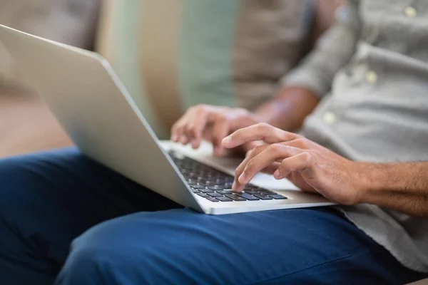 Mid-section of man using laptop in living room — Stock Photo, Image