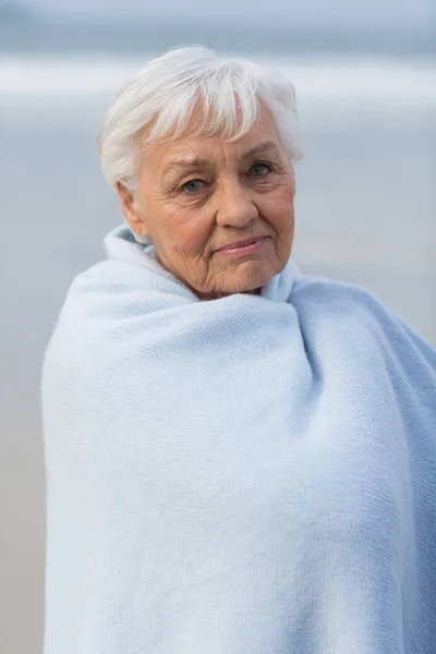 Mulher sênior envolto em xale na praia — Fotografia de Stock