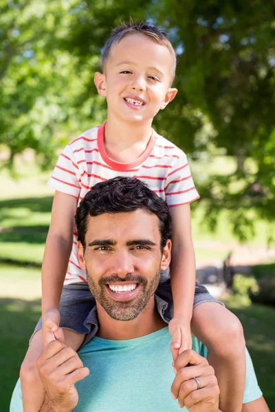 Retrato del padre cargando a su hijo en hombros en el parque — Foto de Stock