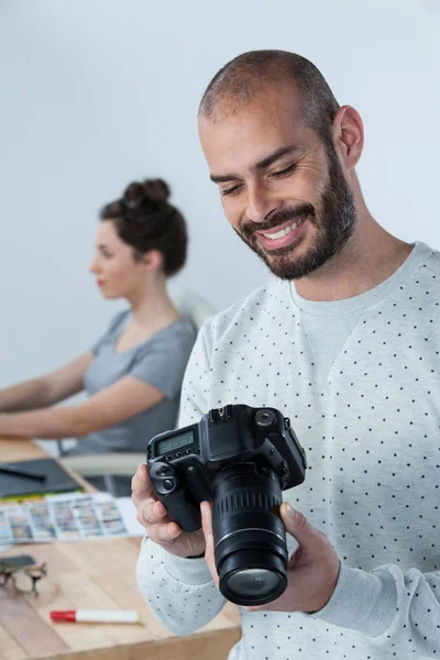 Fotógrafo masculino revisando fotos capturadas em sua câmera digital — Fotografia de Stock