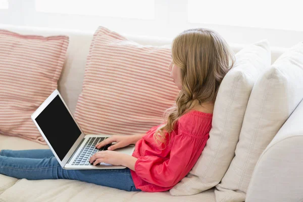 Chica usando el portátil en el sofá en la sala de estar — Foto de Stock