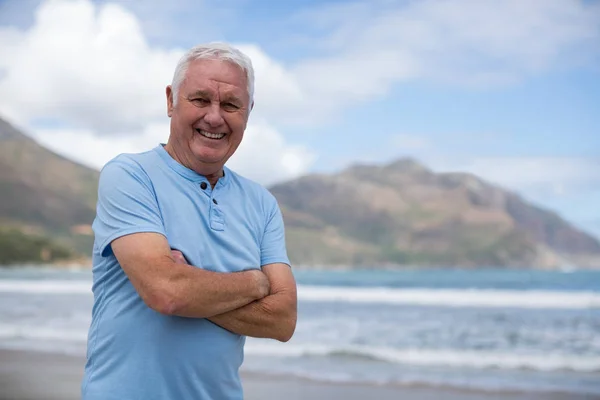 Senior férfi keresztbe a parton állva portréja — Stock Fotó