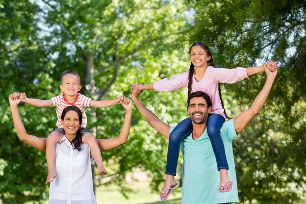 Retrato de padres que llevan a sus hijos al hombro en el parque —  Fotos de Stock